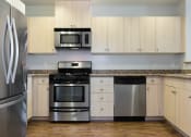 Thumbnail 28 of 29 - Oakland CA Apartments - Aqua Via - White Kitchen with Granite Countertops, Stainless Steel Appliances & Wood-Style Flooring at Aqua Via Apartments, Oakland, 94607