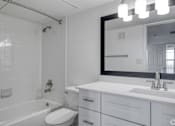 Thumbnail 6 of 29 - A white bathroom with a toilet, sink, and mirror.