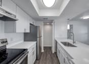 Thumbnail 7 of 29 - A modern kitchen with white cabinets and stainless steel appliances.