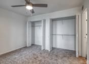 Thumbnail 9 of 29 - A room with a ceiling fan and carpeted floor.