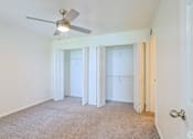 Thumbnail 13 of 29 - A room with a ceiling fan and carpeted floor.