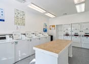Thumbnail 21 of 29 - A laundromat with a row of washers and dryers.