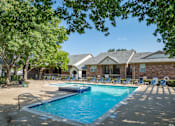 Thumbnail 20 of 29 - A swimming pool surrounded by trees and chairs in front of a house.