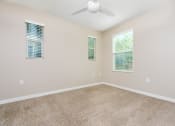 Thumbnail 27 of 60 - a bedroom with a ceiling fan and three windows, with carpeted floors.