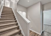Thumbnail 36 of 83 - A staircase with a carpeted runner and white handrails.