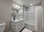 Thumbnail 22 of 83 - A white bathroom with a tub, sink, and mirror.