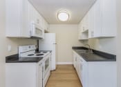 Thumbnail 22 of 86 - One-Bedroom Apartments in Redwood City, CA - Avenue Two - Kitchen with Granite Countertops, White Cabinets, White Appliances, and Hard Surface Flooring at Avenue Two Apartments, Redwood City  , CA