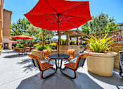 Thumbnail 9 of 40 - A red umbrella is in the middle of a table with chairs around it.
