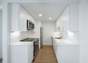 Thumbnail 84 of 86 - a kitchen with white cabinets and a stove and a refrigerator at Avenue Two Apartments, California