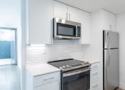 Thumbnail 78 of 86 - a kitchen with white cabinets and stainless steel appliances and a refrigerator at Avenue Two Apartments, California, 94063