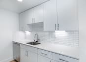 Thumbnail 82 of 86 - a white kitchen with white cabinets and a sink at Avenue Two Apartments, Redwood City  , California
