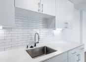 Thumbnail 75 of 86 - a white kitchen with a sink and white tiles at Avenue Two Apartments, Redwood City  , California