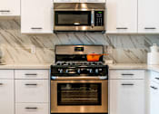 Thumbnail 28 of 29 - A modern kitchen with a stove top oven and microwave above it. at Baker Block, Costa Mesa, CA, 92626