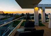 Thumbnail 21 of 29 - A balcony with a table and chairs overlooking a street at sunset. at Baker Block, California, 92626