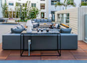 Thumbnail 18 of 29 - A modern outdoor seating area with a large grey sofa and a coffee table. at Baker Block, Costa Mesa, California