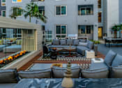 Thumbnail 22 of 29 - A modern outdoor seating area with grey couches and a fire pit. at Baker Block, Costa Mesa, California