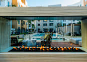 Thumbnail 12 of 29 - A modern outdoor pool area with a fire pit in the foreground. at Baker Block, Costa Mesa, CA, 92626