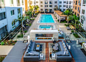 Thumbnail 1 of 29 - A large outdoor area with a pool, seating, and a kitchen area. at Baker Block, Costa Mesa, CA, 92626