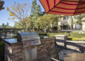 Thumbnail 15 of 25 - an outdoor kitchen with a grill and a table and chairs at 55+ Remington at Ladera Ranch, Ladera Ranch, CA, 92694