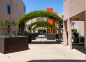 Thumbnail 40 of 50 - a walkway between two buildings with plants and an archway