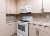 Thumbnail 49 of 50 - a kitchen with white appliances and granite counter tops