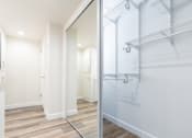 Thumbnail 38 of 77 - a walk in closet with a mirrored closet door in a white room