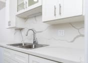 Thumbnail 44 of 77 - a white kitchen with a sink and white cabinets