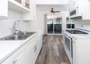 Thumbnail 60 of 77 - a kitchen with white cabinets and a stove and a sink