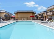 Thumbnail 64 of 77 - a swimming pool with chairs and umbrellas in front of a building