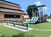 Thumbnail 74 of 77 - a playground with a slide and a bench in front of a building