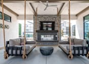 Thumbnail 11 of 87 - Outdoor California Room with a fireplace and two hanging sofas.