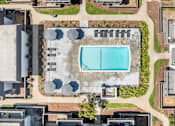 Thumbnail 54 of 91 - An aerial view of a swimming pool surrounded by a concrete patio and a grassy area with trees.