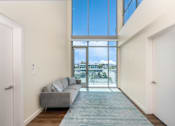 Thumbnail 46 of 127 - A living room with a grey couch and a large window.