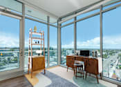 Thumbnail 40 of 127 - A room with a desk and chair in front of a large window with a view of the city.