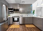Thumbnail 26 of 127 - A modern kitchen with stainless steel appliances and wooden floors.