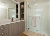 Thumbnail 36 of 127 - A bathroom with a walk-in shower and a vanity with a mirror.