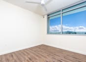 Thumbnail 23 of 127 - A room with a ceiling fan and a window showing a view of the sky and trees.