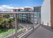 Thumbnail 14 of 127 - A modern building with a glass balcony overlooking a parking lot.