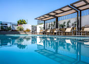 Thumbnail 4 of 127 - A pool with a glass barrier and a white wall with a tree on it.