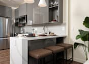 Thumbnail 61 of 127 - A modern kitchen with a white island and stools.