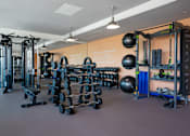 Thumbnail 71 of 127 - A gym with a variety of equipment including weights and a squat rack.