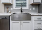 Thumbnail 35 of 97 - Apartments For Rent In South Austin, TX - Casata Austin - Kitchen With Stainless Steel Appliances, Farmhouse Sink, Wood-Inspired Plank Flooring, White Cabinets, And Window With Blinds