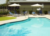 Thumbnail 5 of 97 - Two-Bedroom Apartments in South Austin, TX - Casata Austin - Resort-Style Swimming Pool with Lounge Seats, Tables and Chairs, and Umbrellas.