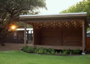 Thumbnail 9 of 97 - One And Two-BR Apartments In South Austin, TX - Casata Austin - Courtyard Covered In Trees With Two Benches, And Tavern Lighting.