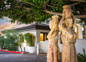 Thumbnail 4 of 48 - A statue of a woman holding a child stands in front of a building.