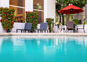 Thumbnail 6 of 48 - A pool with chairs and a red umbrella.