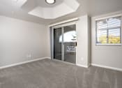 Thumbnail 18 of 48 - A room with a carpeted floor and a sliding glass door leading outside.