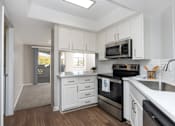 Thumbnail 23 of 48 - A modern kitchen with white cabinets and stainless steel appliances.