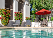 Thumbnail 31 of 48 - A pool with a red umbrella and chairs.