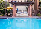 Thumbnail 8 of 80 - an outdoor kitchen next to a swimming pool with a hot tub and a pergola